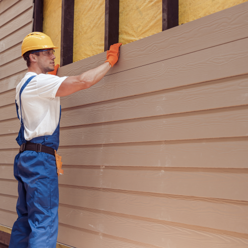 A man installing siding on a house